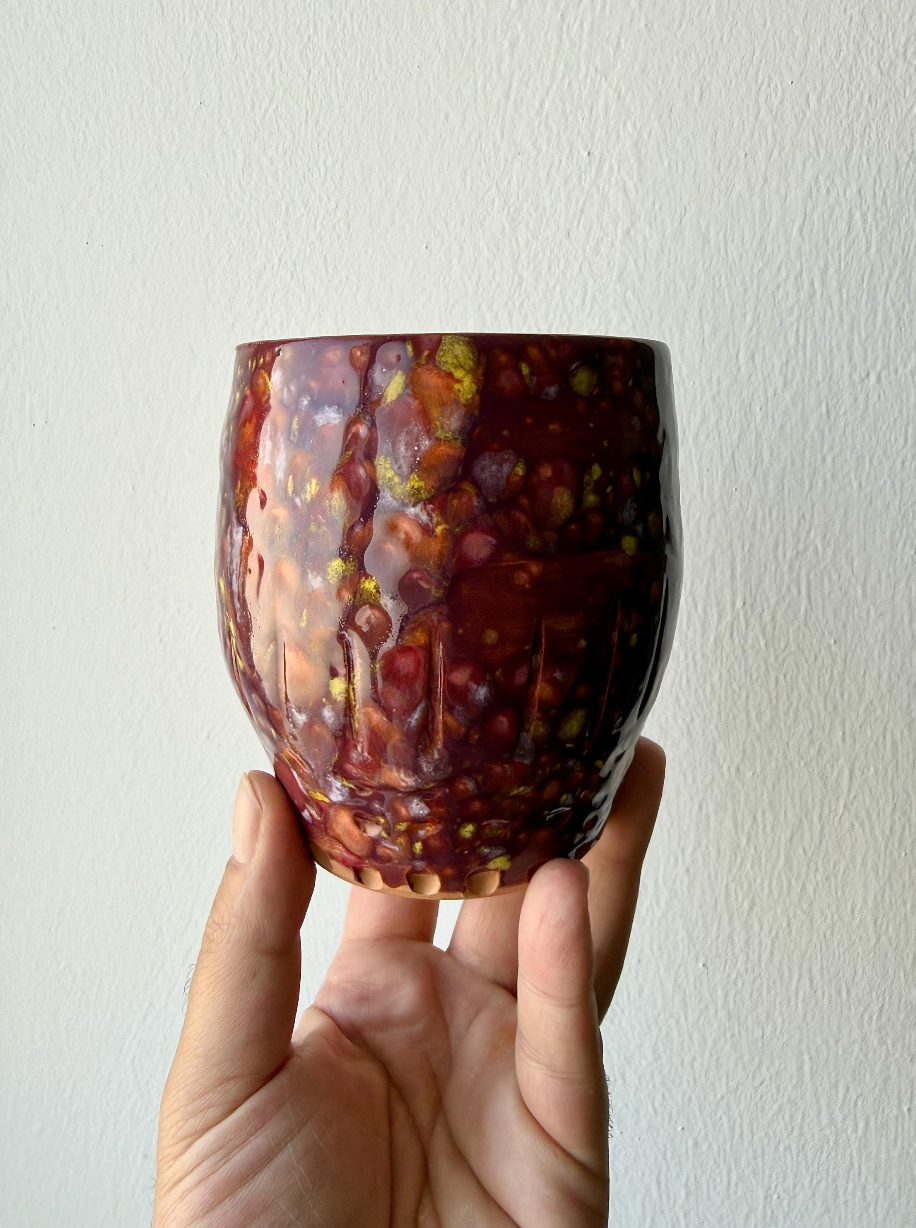 Vasetto in terracotta bordeaux tenuto in mano, vista frontale